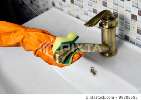 Improper care of brass water faucet, housekeeper wipes tap with abrasive side of washing sponge. 98888585