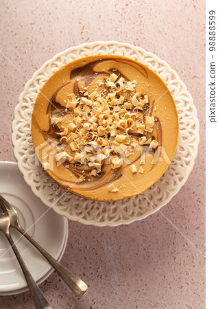 Whole caramel cheesecake on cake stand, neutral warm background Whole caramel cheesecake on cake stand, neutral warm background 98888599