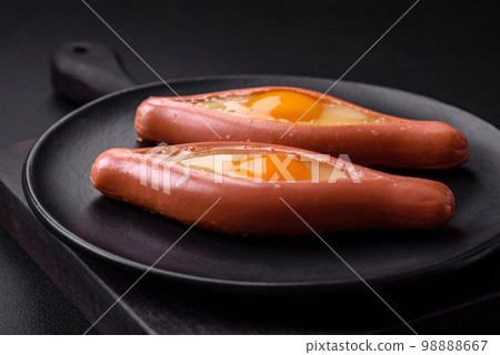 Composite concept of fried eggs inside a cut sausage with spices Composite concept of fried eggs inside a cut sausage with spices 98888667