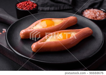 Composite concept of fried eggs inside a cut sausage with spices 98888676