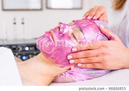Beautician applies a woman a therapeutic cream on her face. Cosmetologist making massage the skin of the forehead. Woman in a spa salon on cosmetic procedures for facial care. . Beautician applies a woman a therapeutic cream on her face. Cosmetologist making massage the skin of the forehead. Woman in a spa salon on cosmetic procedures for facial care. . 98888855