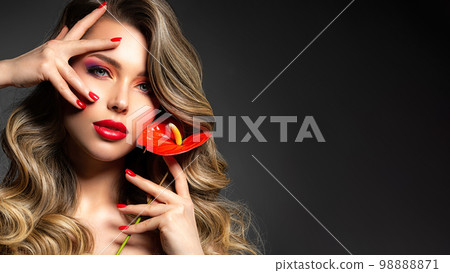 Beautiful white girl with red  flowers. Stunning girl with  Anthurium red. Closeup face of young beautiful blonde woman with a healthy clean skin. Pretty woman with bright makeup and long wavy hair. 98888871