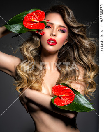 Beautiful blonde with red flowers covers her bare breasts. Portrait of a long-haired blonde with a red flower. Sexy model posing in the studio. Sexy blonde with bright makeup. Beautiful blonde with red flowers covers her bare breasts. Portrait of a long-haired blonde with a red flower. Sexy model posing in the studio. Sexy blonde with bright makeup. 98888876