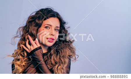 Beautiful model with drawn hearts on her cheeks posing in the studio. Fashion model is photographed in a photo studio looking away from the camera. Beautiful young woman with long hair.. Beautiful model with drawn hearts on her cheeks posing in the studio. Fashion model is photographed in a photo studio looking away from the camera. Beautiful young woman with long hair.. 98888891