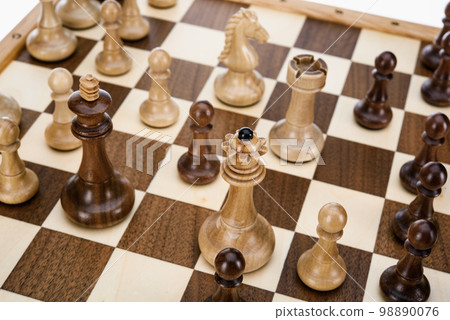 Beige Brown Wooden chess different pieces figures standing on chessboard. Close up game concept competition, Classic Gambit Tournament of confrontation. 98890076
