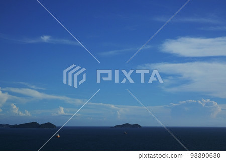 Afternoon scenery with a solitary island floating in the sea and cumulonimbus clouds rising in the distance on the horizon Summer 220727pm Afternoon scenery with a solitary island floating in the sea and cumulonimbus clouds rising in the distance on the horizon Summer 220727pm 98890680