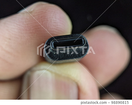 Closeup finger holding USB charger cable on a black background. Closeup finger holding USB charger cable on a black background. 98890815