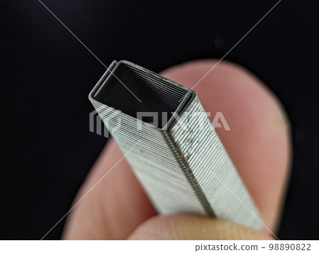 Closeup finger holding staplers bullet on a black background Closeup finger holding staplers bullet on a black background 98890822