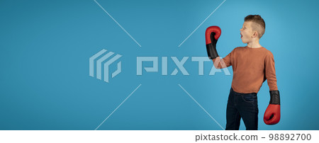 Emotional Boy Wearing Boxing Gloves Looking Aside At Copy Space Emotional Boy Wearing Boxing Gloves Looking Aside At Copy Space 98892700