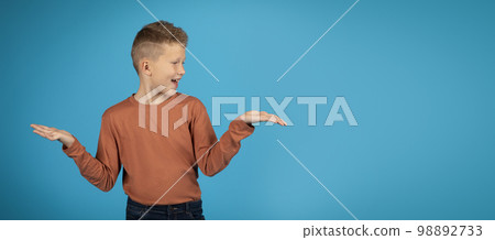 Make Choice. Cheerful preteen boy making scales with his empty palms, 98892733