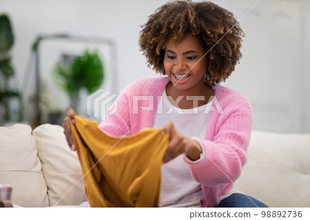 Happy black woman shopaholic checking her new clothes Happy black woman shopaholic checking her new clothes 98892736