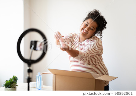 Woman plus size beauty blogger unpacking parcel, showing beauty product 98892861