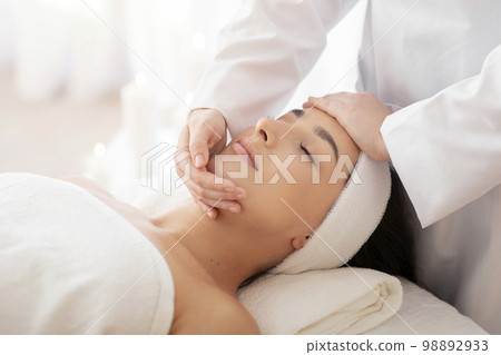 Masseuse Lady Making Face Lifting Massage To Indian Woman In Spa Salon 98892933