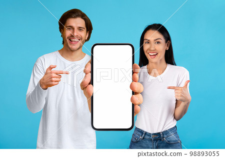 Check This. Happy couple pointing at smartphone with white blank screen Check This. Happy couple pointing at smartphone with white blank screen 98893055
