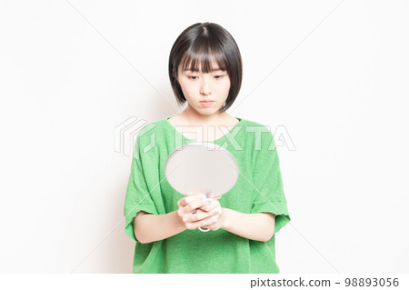 年輕女子在手鏡中看著自己的臉 年輕女子在手鏡中看著自己的臉 98893056
