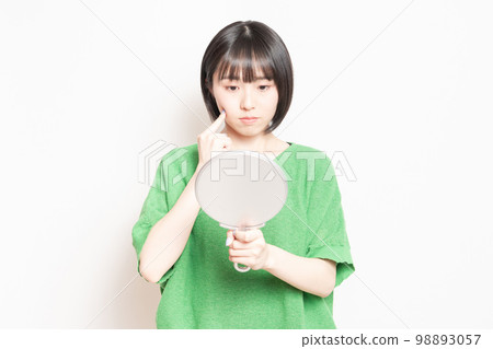 年輕女子在手鏡中看著自己的臉 年輕女子在手鏡中看著自己的臉 98893057