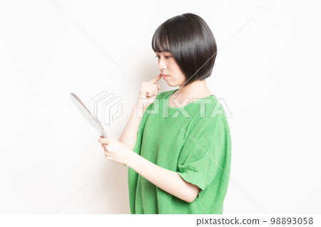 年輕女子在手鏡中看著自己的臉 年輕女子在手鏡中看著自己的臉 98893058