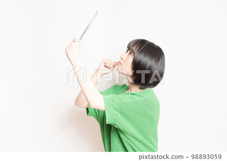 Young woman looking at her face in a hand mirror Young woman looking at her face in a hand mirror 98893059