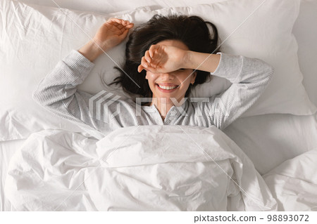 Glad smiling young european woman sleeping on white bed, waking up, enjoying vacation, good morning 98893072