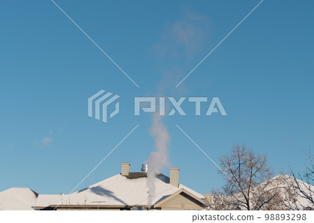 Smoke coming out of the chimney of a house against the blue sky in winter Smoke coming out of the chimney of a house against the blue sky in winter 98893298