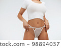 Faceless gorgeous woman with hands on thighs posing in studio 98894037