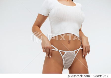 Faceless gorgeous woman with hands on thighs posing in studio 98894037
