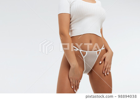 Faceless gorgeous woman with hands on thighs posing in studio 98894038