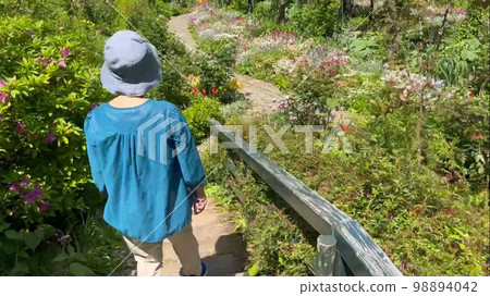 Senior woman walking in flower garden 98894042