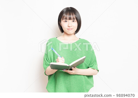 年輕女子用圓珠筆在筆記本上寫字 年輕女子用圓珠筆在筆記本上寫字 98894070