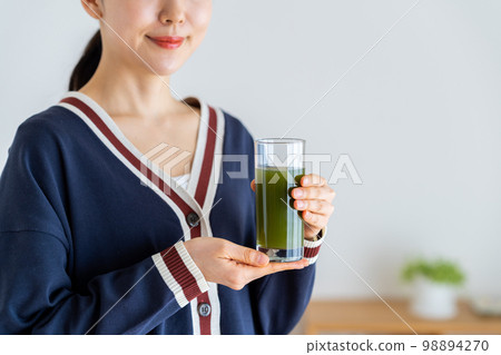A young woman drinking green juice 98894270