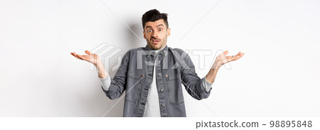 I dont know. Clueless young man shrugging and looking confused, have nothing to say, standing unaware on white background 98895848