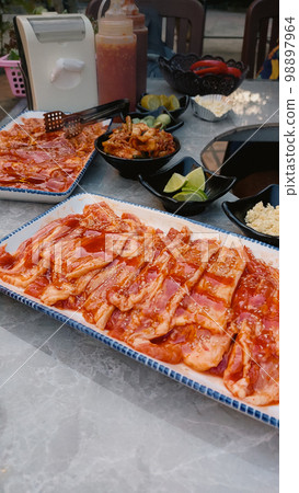 Vertical shot of meat slices, kimchi and vegetables in a korean barbecue setup or gogi-gui Vertical shot of meat slices, kimchi and vegetables in a korean barbecue setup or gogi-gui 98897964