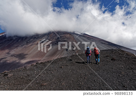 Climbers walking along the ridgeline of Mt. Hoei and the mountainside of Mt. Fuji with clouds Climbers walking along the ridgeline of Mt. Hoei and the mountainside of Mt. Fuji with clouds 98898133