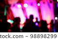 Blurred silhouettes of crowd of people dancing on the dance floor of a night club under the light of colored spotlights and lasers. 98898299