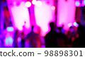 Blurred silhouettes of crowd of people dancing on the dance floor of a night club under the light of colored spotlights and lasers. 98898301