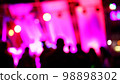 Blurred silhouettes of crowd of people dancing on the dance floor of a night club under the light of colored spotlights and lasers. 98898302
