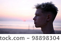 Thoughtful guy looks into the distance on the beach during sunset 98898304