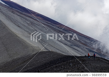 登山者沿著寶永山的山脊線和雲霧繚繞的富士山山腰行走 登山者沿著寶永山的山脊線和雲霧繚繞的富士山山腰行走 98899559