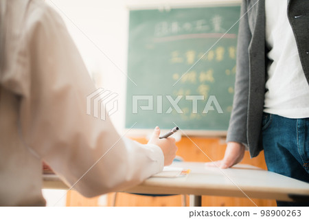 Male high school teacher teaching a female student Male high school teacher teaching a female student 98900263