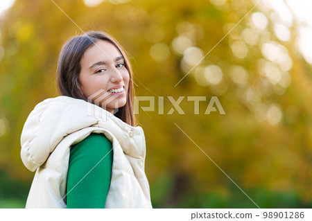 Sensual young woman turning to smile at the camera outdoors 98901286