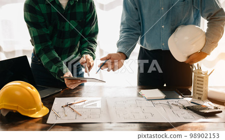 Creative architect projecting on the big drawings in the dark loft office or cafe in sun light. 98902153