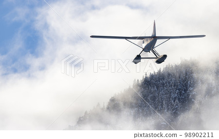 Floatplane flying over the Canadian Mountain Landscape. Adventure Composite 98902211