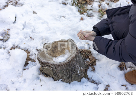 一個人坐在樹樁前,在隆冬的雪中手握著寒冷的手 一個人坐在樹樁前,在隆冬的雪中手握著寒冷的手 98902768