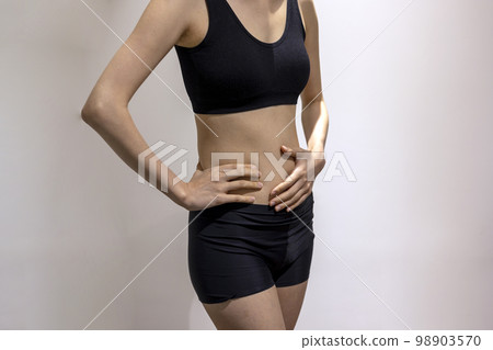 穿著黑色運動服的女人站在她的身邊和肚子上 穿著黑色運動服的女人站在她的身邊和肚子上 98903570