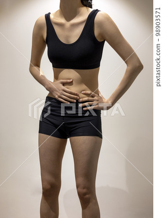 Woman standing on her side and stomach while wearing black sportswear Woman standing on her side and stomach while wearing black sportswear 98903571