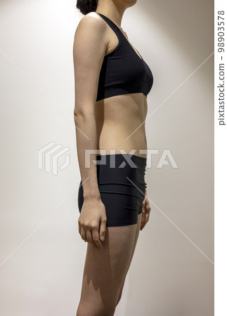 A woman with a slim and healthy body standing with correct posture wearing black sportswear 98903578
