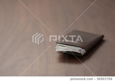 Full grain leather wallet with us dollars on walnut table Full grain leather wallet with us dollars on walnut table 98903768
