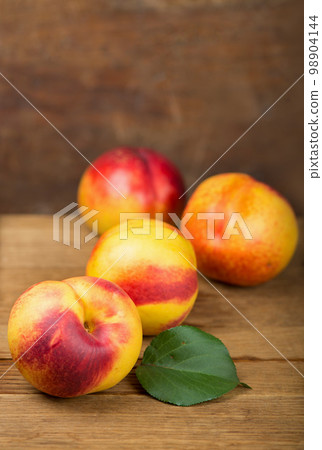 fresh nectarines with leaves on wooden background. fresh nectarines with leaves on wooden background. 98904144