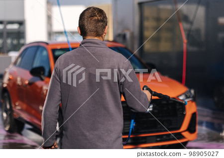 Worker cleaning car using high pressure water. Self servise car washing. Clean auto Worker cleaning car using high pressure water. Self servise car washing. Clean auto 98905027