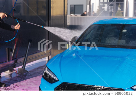 Worker cleaning car using high pressure water. Self servise car washing. Clean auto 98905032